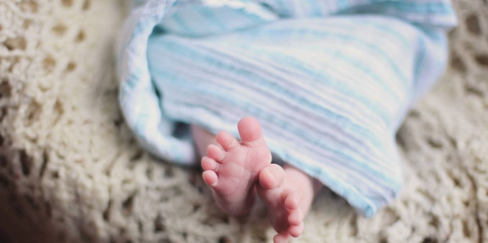 close-up of baby feet under a blue blanket