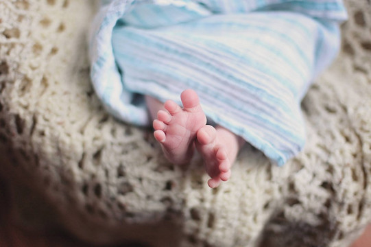 Babyfüße Nahaufnahme Babyfüße die aus einer blauen Decke schauen