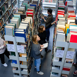 Studierende suchen nach Büchern in der Bibliothek.