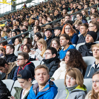 Studierende des ersten Semesters sitzen bei der Erstsemesterbegrüßung auf den Rängen im Stadium.