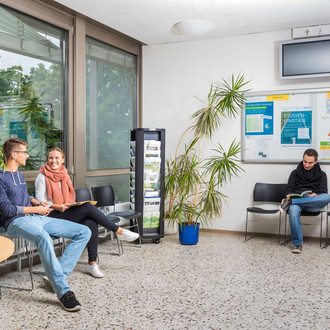 Studierende sitzen im Wartebereich der Studienberatung