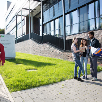 Studierende stehen vor einem Gebäude.