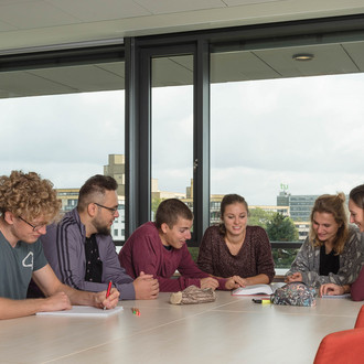 Studierende sitzen mit Lernunterlagen am Tisch.