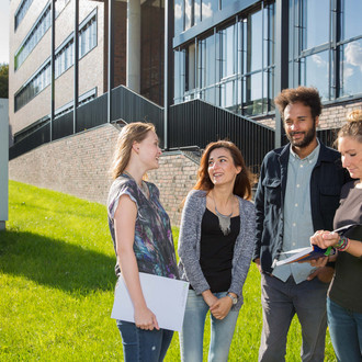 Vier Studierende stehen vor dem neu errichteten Physikgebäude.
