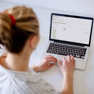 Foto einer Frau, die auf einen Laptop blickt.