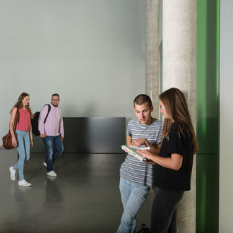 Zwei Studierende unterhalten sich, zwei andere kommen auf sie zu.