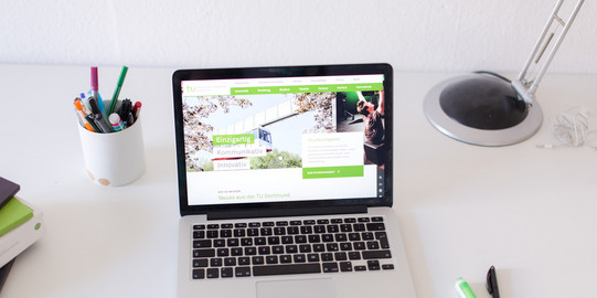 Arbeitsplatz mit Laptop Arbeitsplatz am Schreibtisch, mit eingeschaltetem Laptop und Stiften.