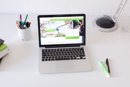 Arbeitsplatz mit Laptop Arbeitsplatz am Schreibtisch, mit eingeschaltetem Laptop und Stiften.