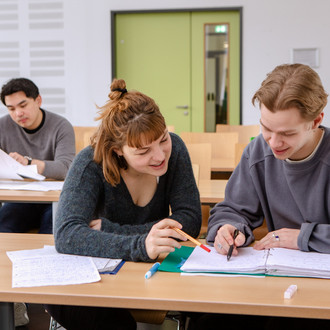 Studierende im Seminarraum sitzen zusammen und arbeiten.