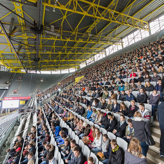 Studierende des ersten Semesters sitzen im Stadion bei der Erstsemesterbegrüßung auf den Rängen.