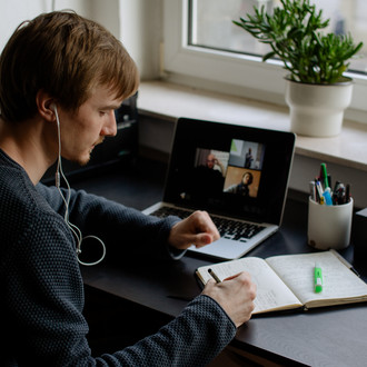 Ein Student arbeitet mit Laptop und Notizbuch.