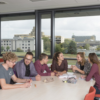 Studierende sitzen mit Lernunterlagen am Tisch.