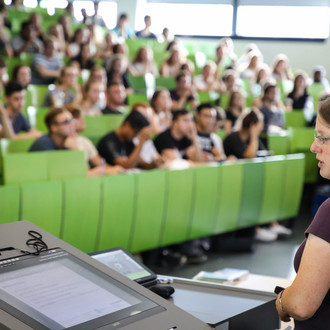 Dozierende sitzt vor Studierenden im Hörsaal im Seminargebäude. 