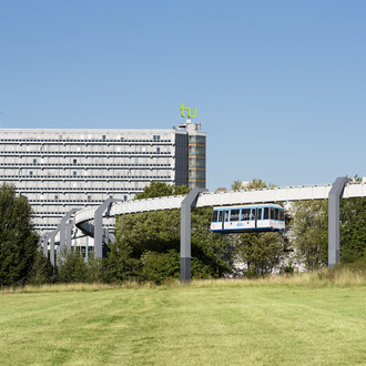 Das Mathegebäude mit TU-Logo und die H-Bahn