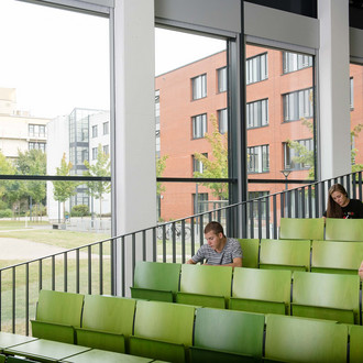 Drei Studierende sitzen im Hörsaal.
