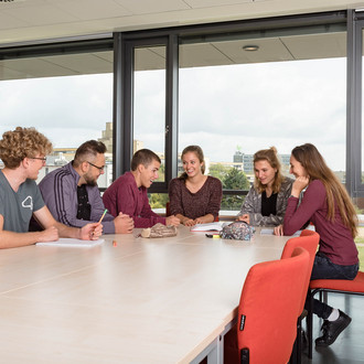 Studierende sitzen mit Lernunterlagen am Tisch.