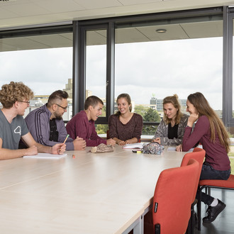 Studierende sitzen mit Lernunterlagen am Tisch.