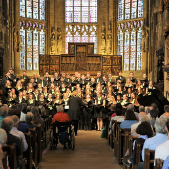 Ein Chor steht während eines Gottesdienstes in einer Kirche, hält Gesangsbücher in der Hand und singt.