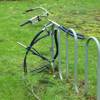 Ein gestohlenes Fahrrad mit nur einem Lenker ist auf grünem Rasen angeschlossen.