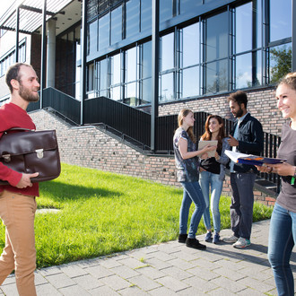 Studierende stehen vor einem Gebäude.