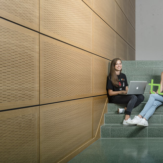 Zwei Studentinnen sitzen mit Laptop und TU-Logo auf einer Treppe.