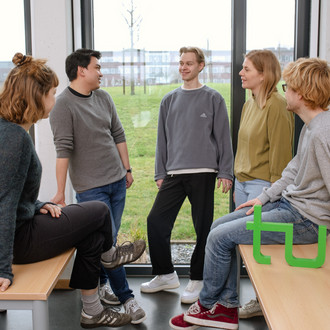 Ein Gruppenfoto von Studierenden im Seminarraum mit dem TU Dortmund Logo.