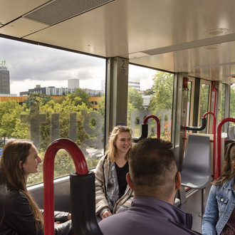 Vier Studierende sitzen sich gegenüber in der H-Bahn und unterhalten sich.