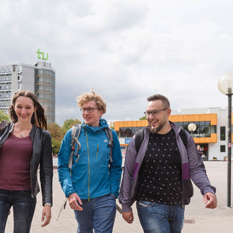 Drei Studierende laufen über die Mensabrücke und unterhalten sich.