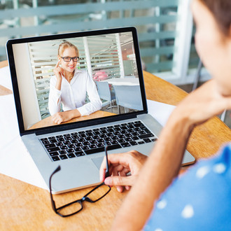 Frau sitzt und hält eine Videokonferenz auf ihrem Laptop mit einer anderen Frau ab