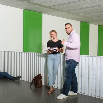 Studierende stehen vor einem Geländer, einer streckt den Daumen hoch.