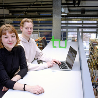 Zwei Studierende sitzen an einem Tisch in der Bibliothek.
