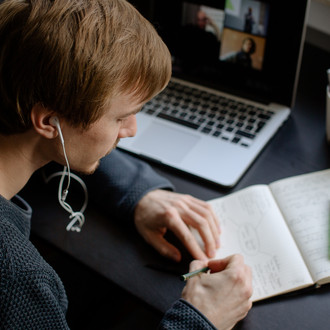 Ein Student arbeitet mit Laptop und Notizbuch.