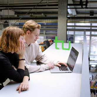 Zwei Studierende sitzen an einem Tisch in der Bibliothek und arbeiten.