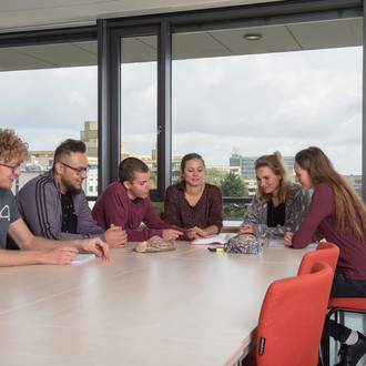 Studierende sitzen mit Lernunterlagen am Tisch.