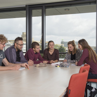 Studierende sitzen mit Lernunterlagen am Tisch.