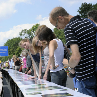 Menschen stehen auf der gesperrten Autobahn und sehen sich eine Fotoausstellung an.