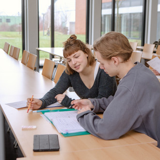 Studierende im Seminarraum sitzen zusammen und arbeiten.