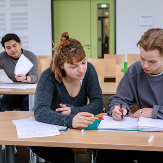 Studierende im Seminarraum sitzen zusammen und arbeiten
