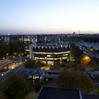 Die Bibliothek und Mensabrücke beleuchtet in der Abenddämmerung.