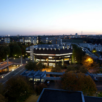 Die Bibliothek und Mensabrücke beleuchtet in der Abenddämmerung.