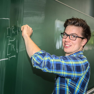 Ein Student schreibt eine mathematische Gleichung an eine Tafel
