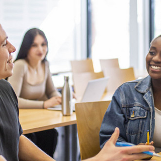 Studierende sitzen im Seminarraum und reden miteinander.