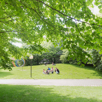 Studierende auf der Wiese mit den Spektralringen im Hintergrund im Sommer