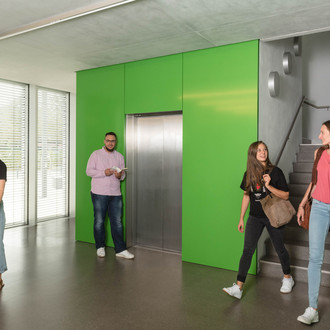 Studierende laufen im Treppenhaus und vor dem Aufzug.
