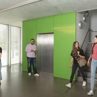 Studierende laufen im Treppenhaus und vor dem Aufzug.