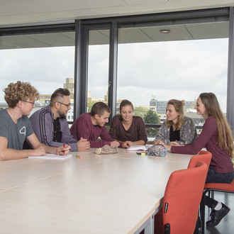 Studierende sitzen mit Lernunterlagen am Tisch.