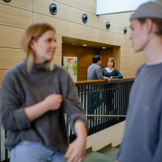 Zwei Studierende stehen nebeneinander und unterhalten sich.