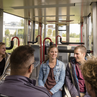 Mehrere Studierende fahren mit der H-Bahn.