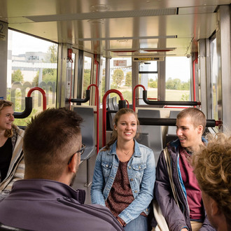 Mehrere Studierende fahren mit der H-Bahn.