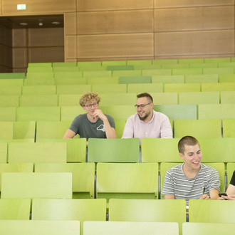 Vier Studierende sitzen in einem Hörsaal.